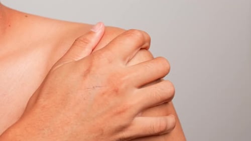 Gently squeezing each shoulder with the opposite hand.