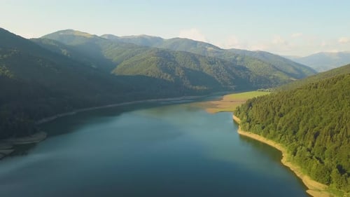 Aerial View of Big Lake with Clear Blue Water Between High Mountain Hills Covered with Dense