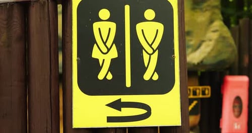 Sinal amarelo e preto indica banheiros públicos para homens e mulheres com seta