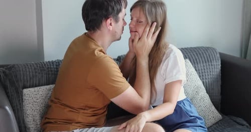 Loving Couple Embracing and Kissing on Couch