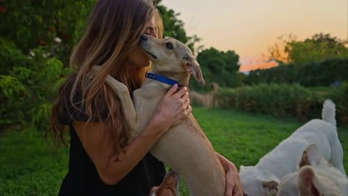 Woman Cuddling Adorable Dog in Rural Sunset