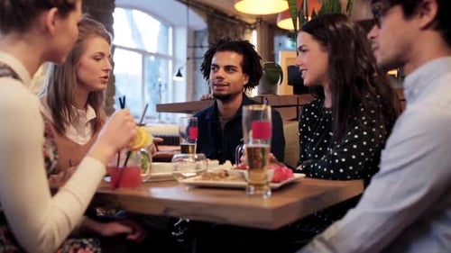 Happy multiethnic friends enjoying food drinks and leisure time at a cafe
