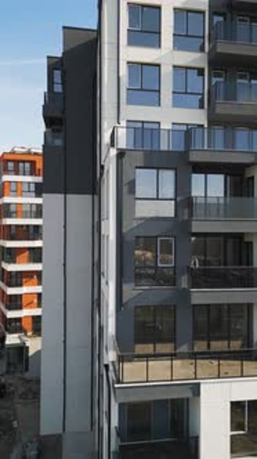 Toma aérea con un Zumbido de la fachada de un edificio residencial moderno con paneles negros y balcones blancos