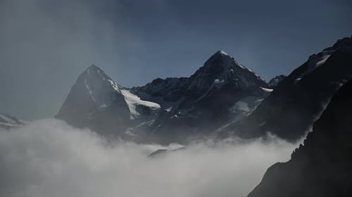Atmosphärische Wolken steigen vor den dramatischen schneebedeckten Bergen in der Schweiz auf