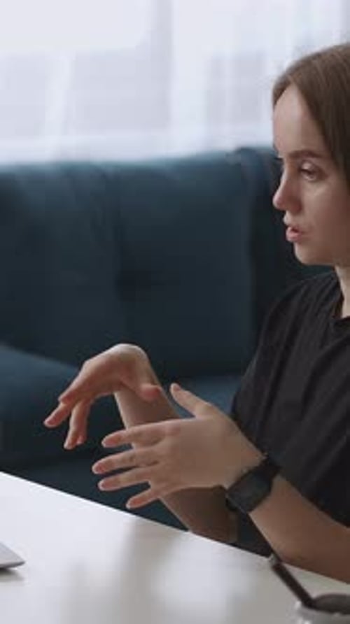 Jeune femme concentrée engagée dans une discussion détaillée en utilisant des gestes expressifs de la main en position assise