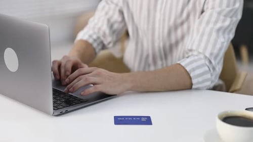 Man Typing on Laptop With Credit Card Nearby