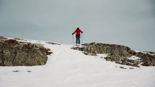 Freeskier jumps down the rocky slope during winter season