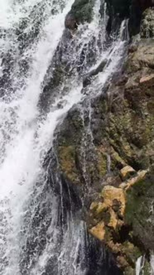 Waterfall Cascading Down Rocky Terrain in Daylight