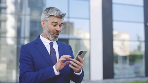 Man Celebrating Good News on Smartphone Outdoors