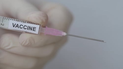 Impfflüssigkeit, die aus der Nadel einer Einwegspritze tropft. - Nahaufnahme