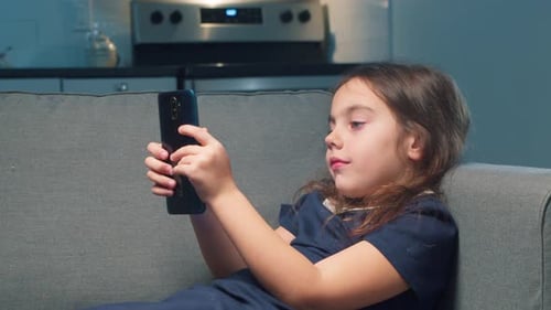 Child on Couch Uses Smartphone