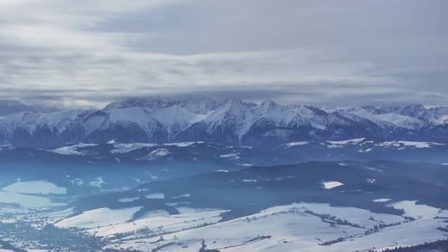 Snow-covered mountains and lakes in winter landscape over cast sky