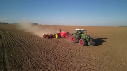 Green tractor works on the field sowing sunflower. Tractor planting corn in Ukraine