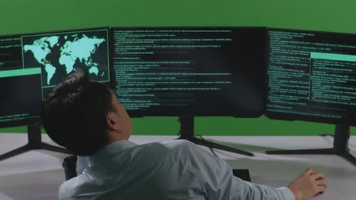 Back View Of Bored Asian Man Developer Write Code With Multiple Computer Screens In Green Screen