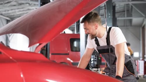 A Car Mechanic Examines a Car at a Car Service Performing a Number of Tests and Checks