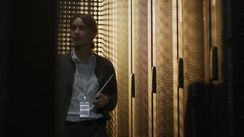 Young Female Data Center Specialist Walking Through Server Room