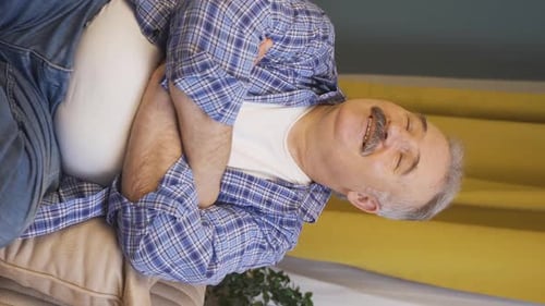 Man Lying On Couch Experiencing Stomach Pain