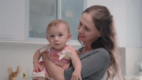 Woman Holding Baby in Her Arms Indoors