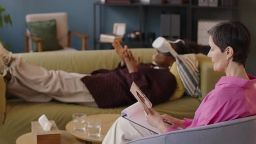 African American Woman in VR Headset Lying on Sofa at Psychologist Office