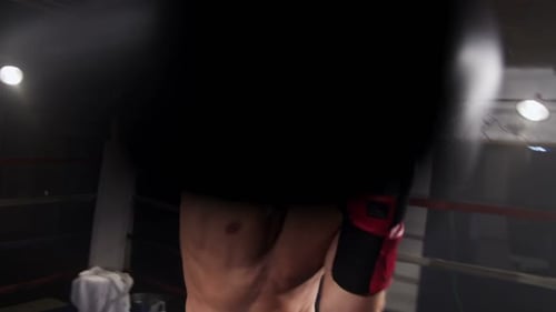 Intense shirtless man training in a boxing ring