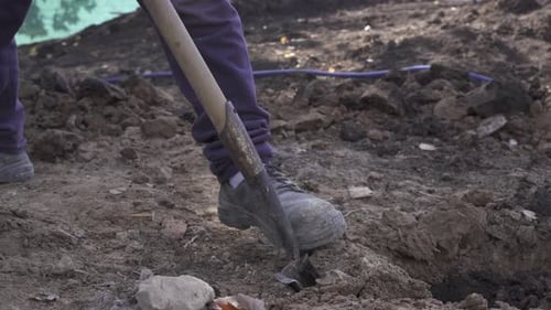 Unrecognizable man with shovel digging hole. Handheld and close up