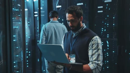 Technician Works on Laptop in Modern Server Room