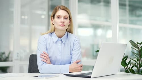 Portrait of a serious successful businesswoman sitting at the workplace in a modern office.