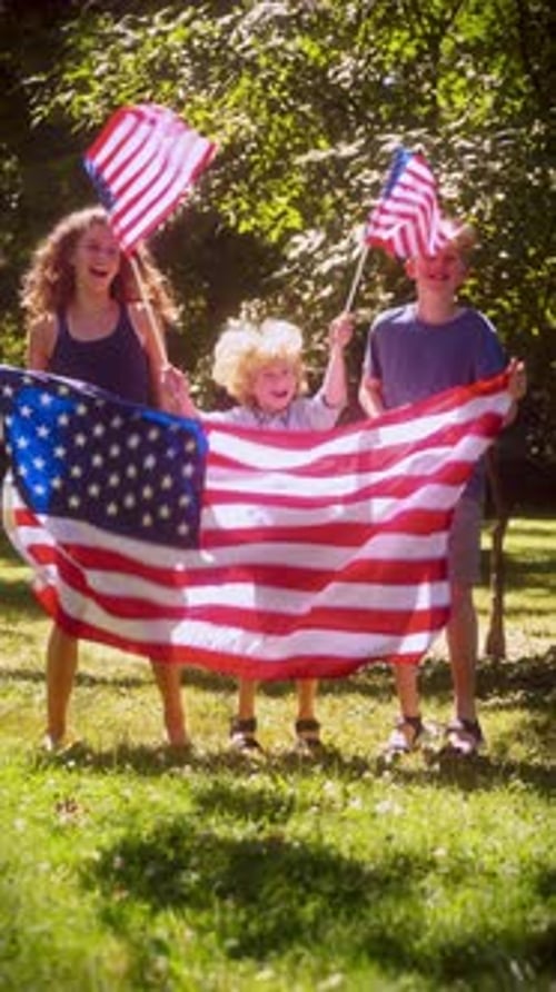 Three Children Displaying American Flags Outdoors