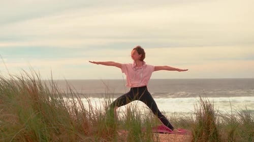 Yoga-Übungen mit windigem Herbstwetter und Meeresuntergang im Hintergrund