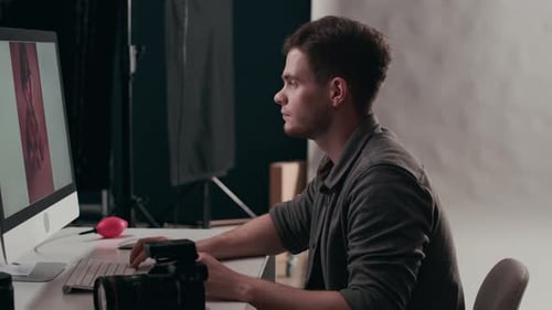 Photographer Retouching Photos at Computer Workstation
