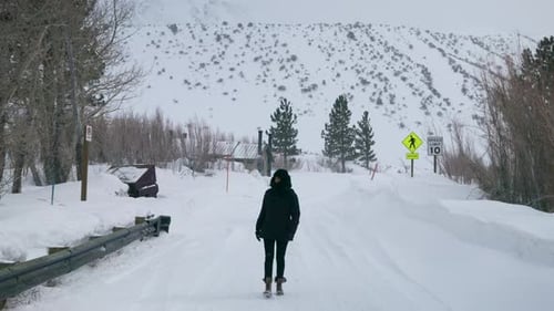 Woman in Black Winter Clothes Walking Along Lonely Road in Mountains Blizzard