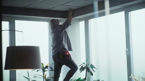 Technician Installing Security Camera in Bright Office