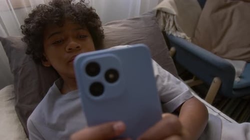 Child Relaxing in Bed with Phone