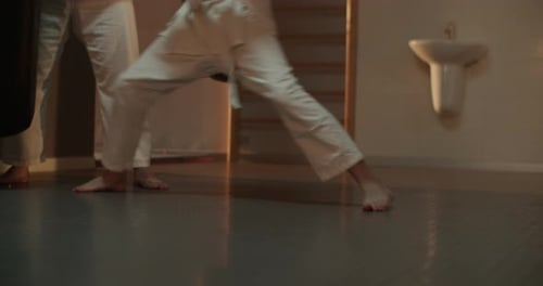 Barfuß-Karate-Student springt mit Sensei auf einen angreifenden Boxsack