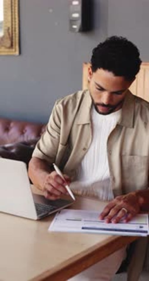 Businessman, writing and documents with laptop in cafe for stock control or inventory management