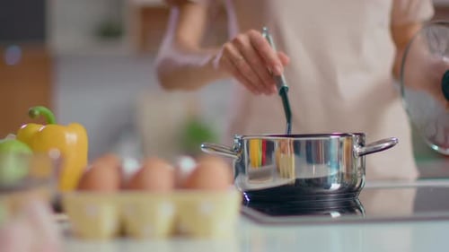 Chef cocinando sopa en la estufa en la cocina doméstica, jovencita relajándose