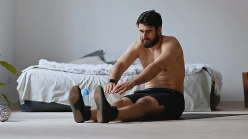 Man Stretching on Yoga Mat in Bedroom