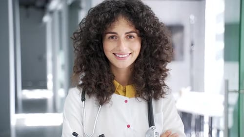 Portrait of happy smiling female doctor in white coat looking at camera in modern hospital clinic.