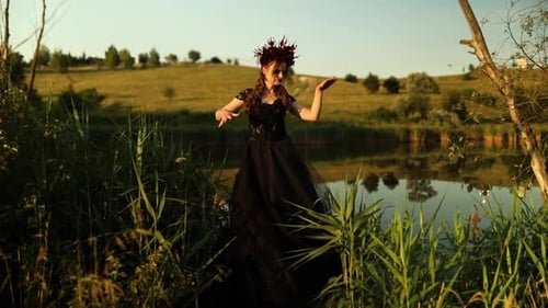 Woman in Costume Poses by Lake at Sunset