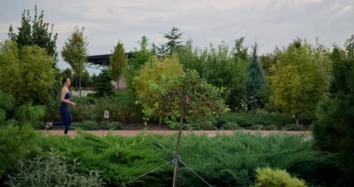 Side View of a Happy Brunette Girl in a Blue Sports Uniform Running and Looking at Her Surroundings