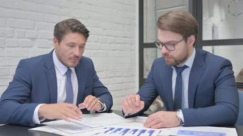 Businessmen Discussing Financial Data in Modern Office