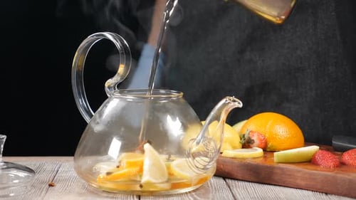 Closeup Shot of Boiled Water Being Poured Into Teapot Wuth Fruit