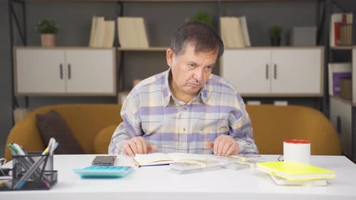 Man Counting Money and Writing in Notebook