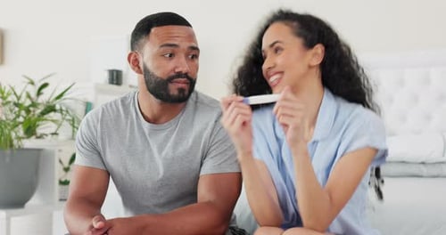 Excited Couple Looking at Pregnancy Test in Bedroom