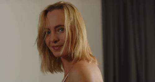 Close up of a beautiful young woman dressed in a pink bra sensually smiling at the camera