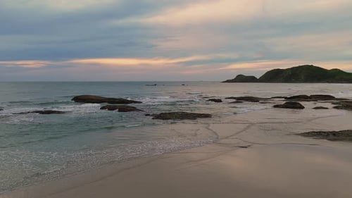 High angle view of beach with gentle waves and repetitive waves near the sunbathers