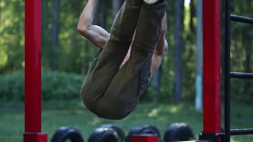 Workout in the park. Young caucasian man with lean body works out in the park and performs ABS exerc