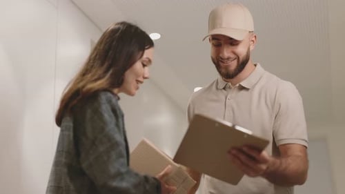 Friendly Delivery Man Handing Package to Young Woman