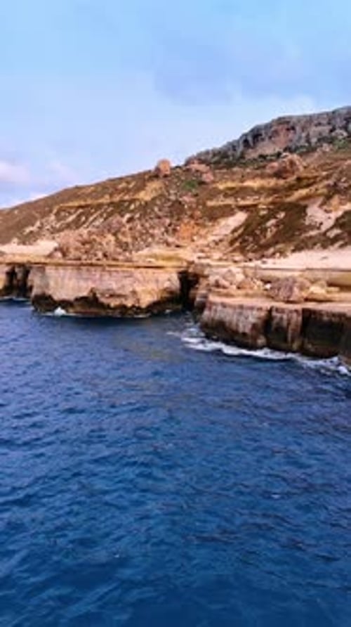 Flying away from the bare rocks at the coast of Malta. Cliffs at the shore of the Mediterranean Sea.