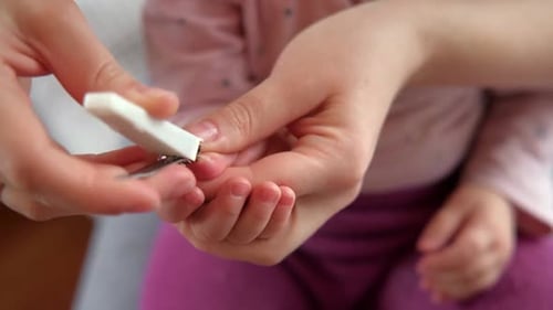 Adult Carefully Clipping Child's Fingernails at Home